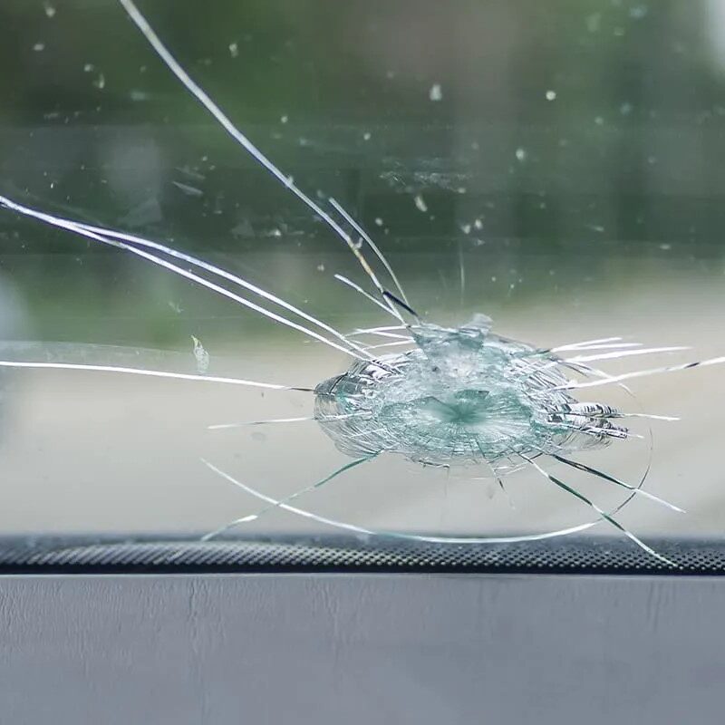 Parabrezza di un’auto danneggiato con crepa centrale, pronto per la sostituzione.